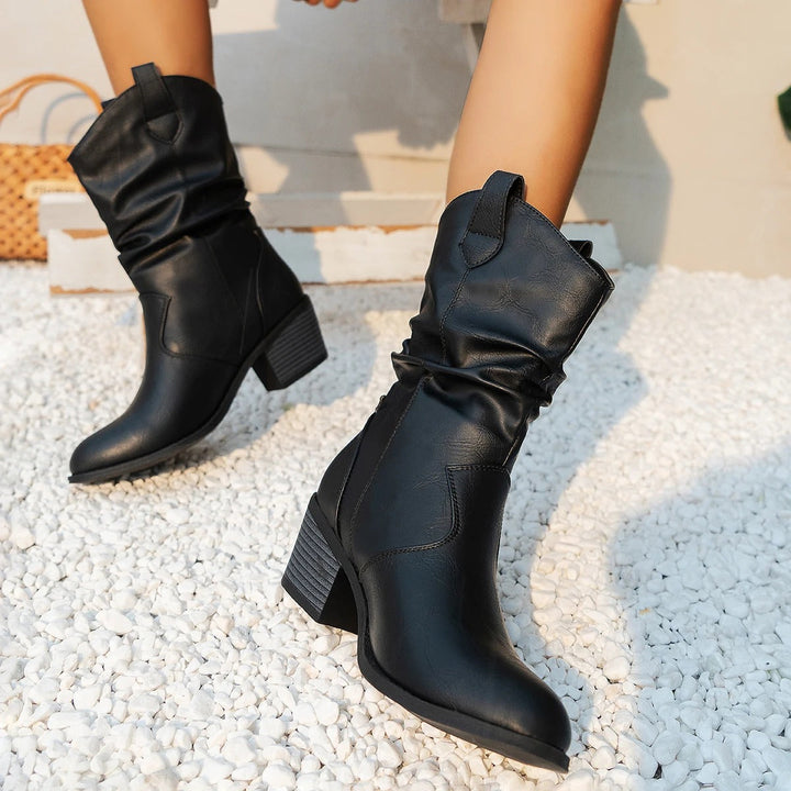 Zwarte leren dameslaarzen met blokhak op witte kiezelstenen, stijlvolle herfst- en wintermode, comfortabele en trendy schoenen.