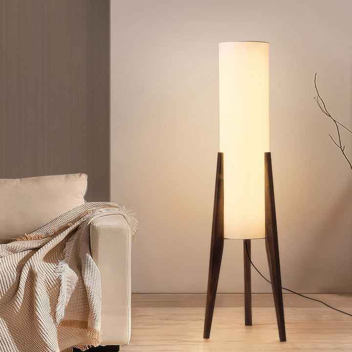 Hoge LED-vloerlamp met houten driepoot en cilindrische stoffen kap met tafel