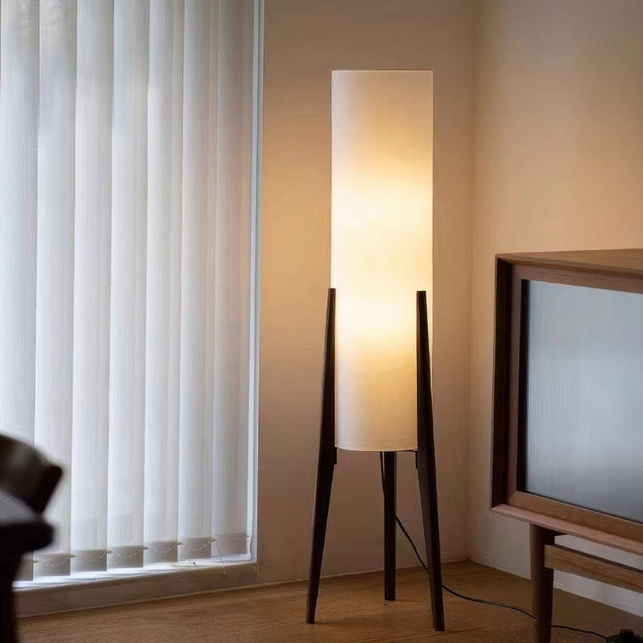 Hoge LED-vloerlamp met houten driepoot en cilindrische stoffen kap met tafel
